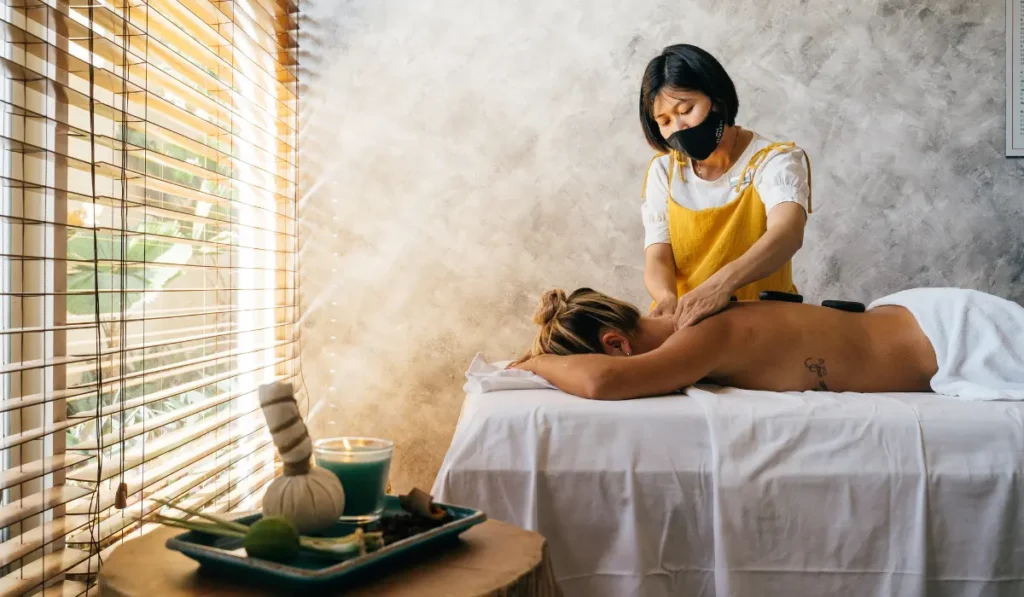 Outcall massage Bangkok in a hotel room—therapist setting up, guest in comfy attire, calm lighting—first-timer etiquette scene.